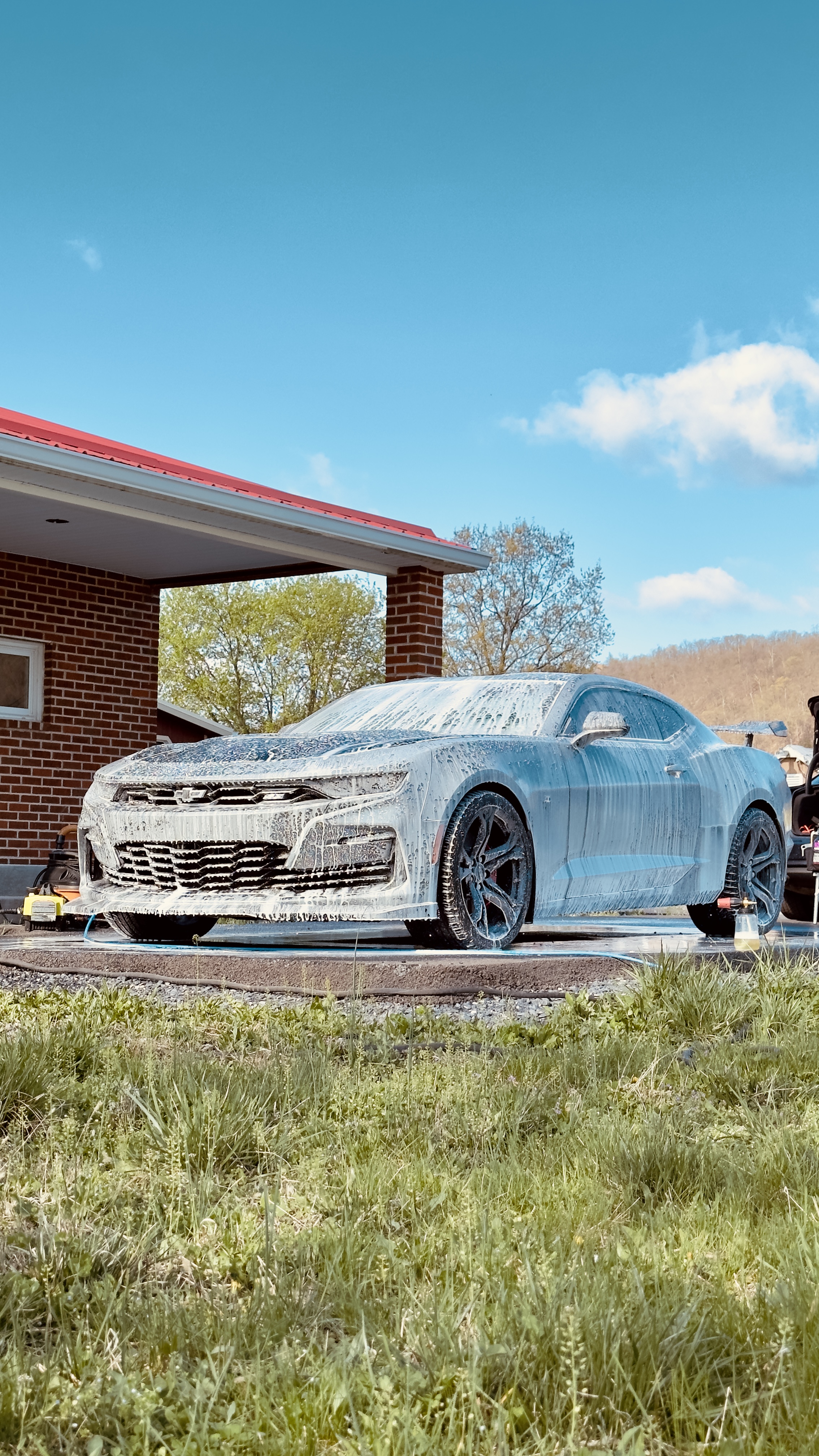 Chevrolet Camaro covered in snow foam under blue sky
