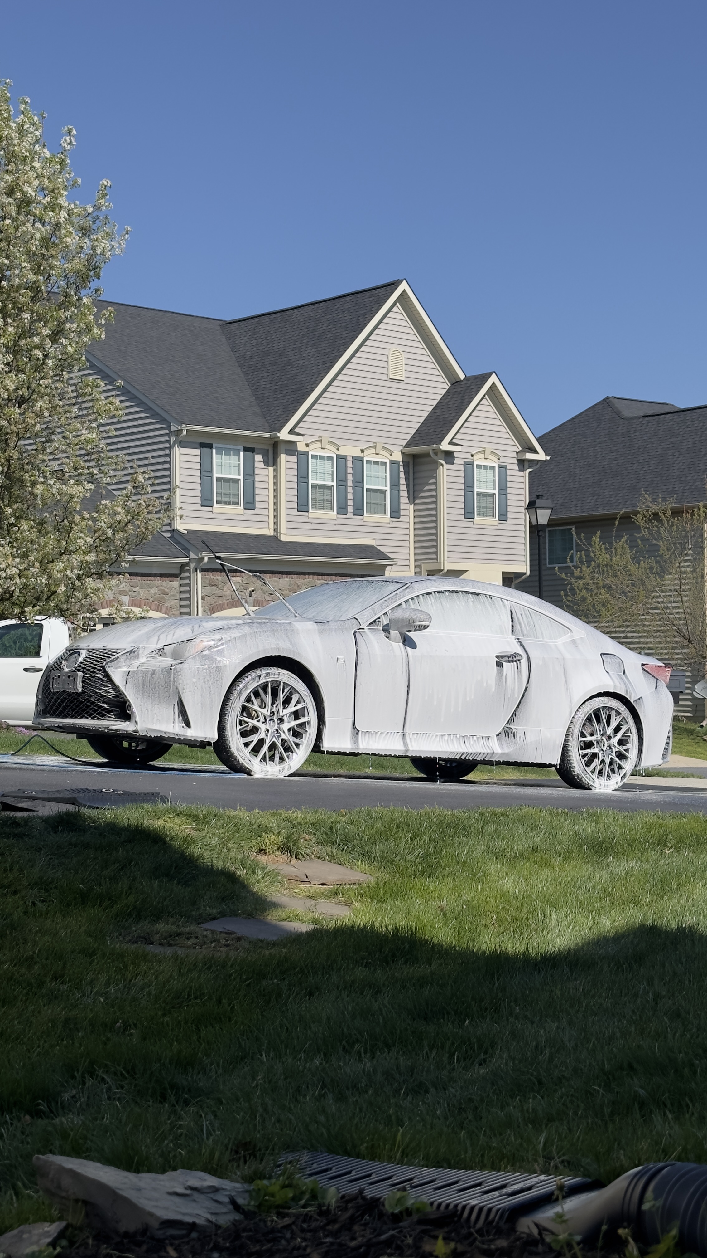 White Lexus RC coupe under thick snow foam on a suburban street