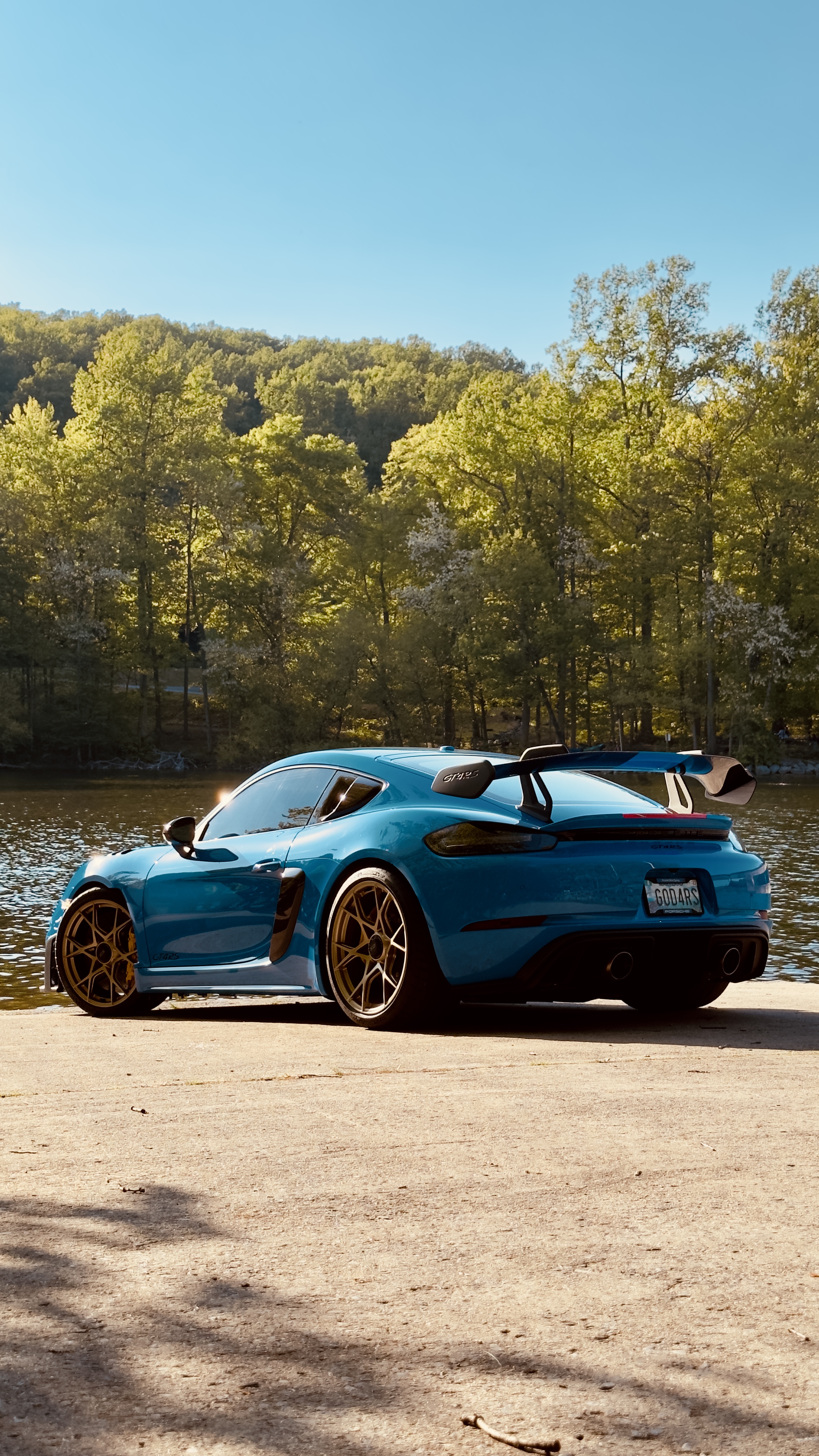Miami-blue Porsche 718 Cayman GT4 detailed to a glossy finish, lakeside